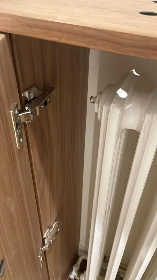 Radiateur en fonte avec purgeur derrière un meuble